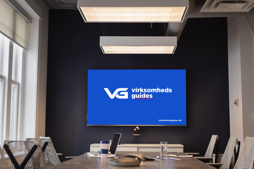 Moderne mødelokale hos Virksomhedsguides.dk med logo på skærmen, der repræsenterer vores professionelle rådgivning for danske iværksættere.