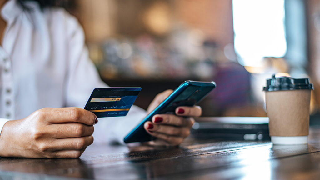 En iværksætter tjekker sin netbank på mobilen efter at have lavet en grundig sammenligning af erhvervskonto priser for sin nye virksomhed.