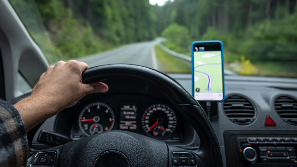 Skattefri kørselsgodtgørelse 2026: Se takster og regler her En forretningsmand tracker sin rute på en smartphone for at få udbetalt sin skattefri kørselsgodtgørelse 2026.